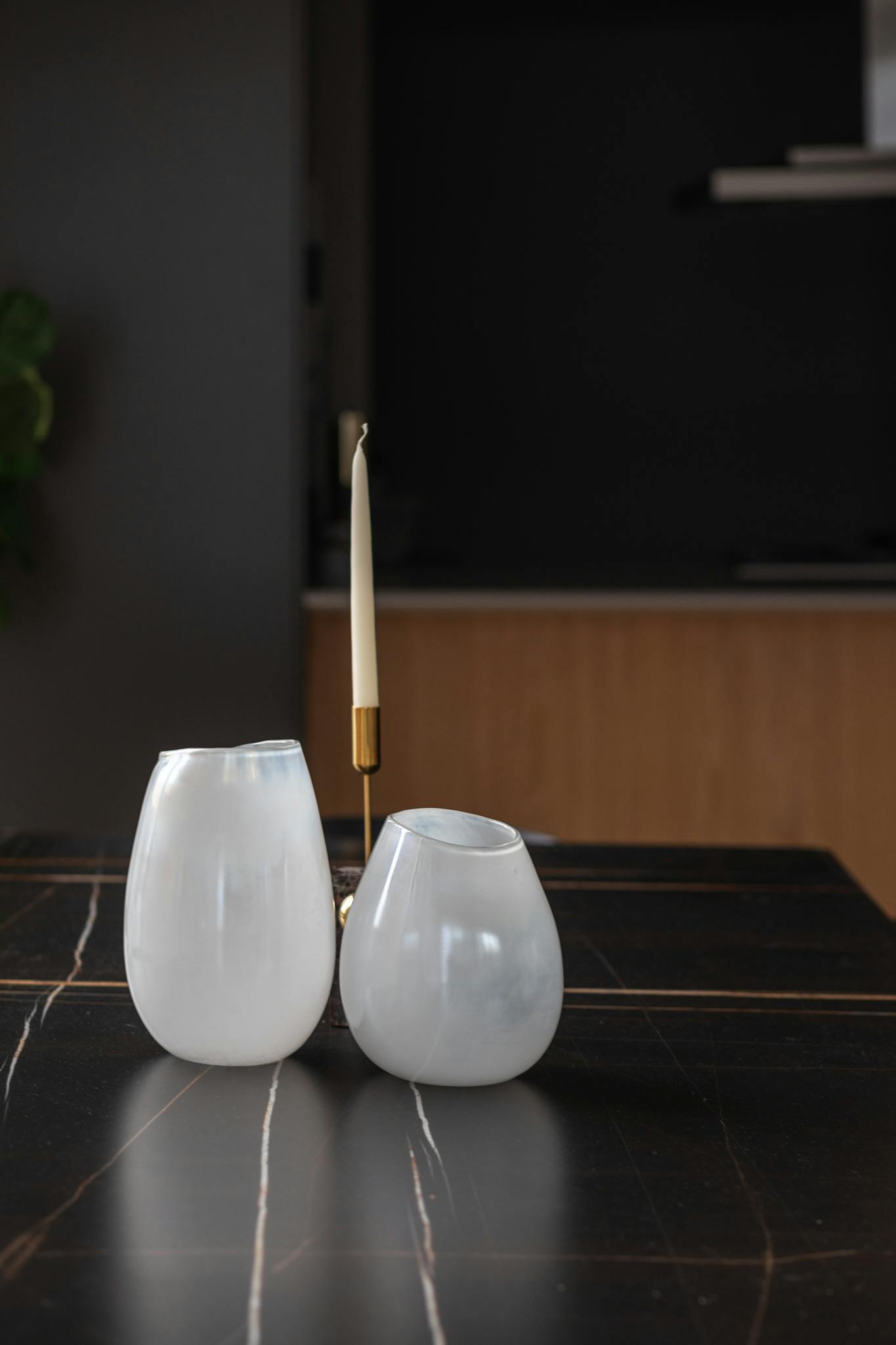 Decorative ceramic vases and candle holder on a marble table reflecting minimalist elegance.